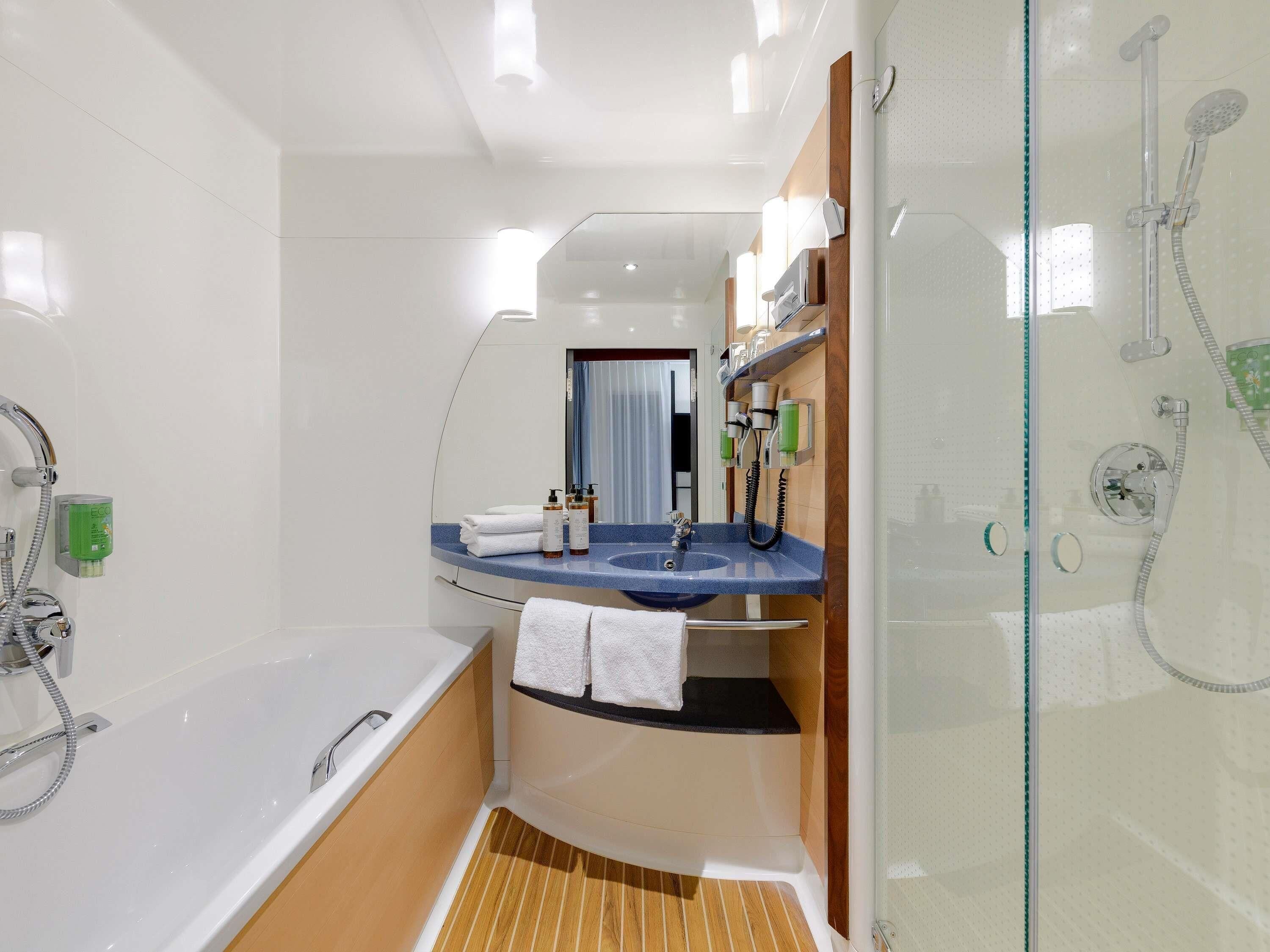Un baño moderno con bañera, ducha, tocador con espejo y un perchero para toallas.