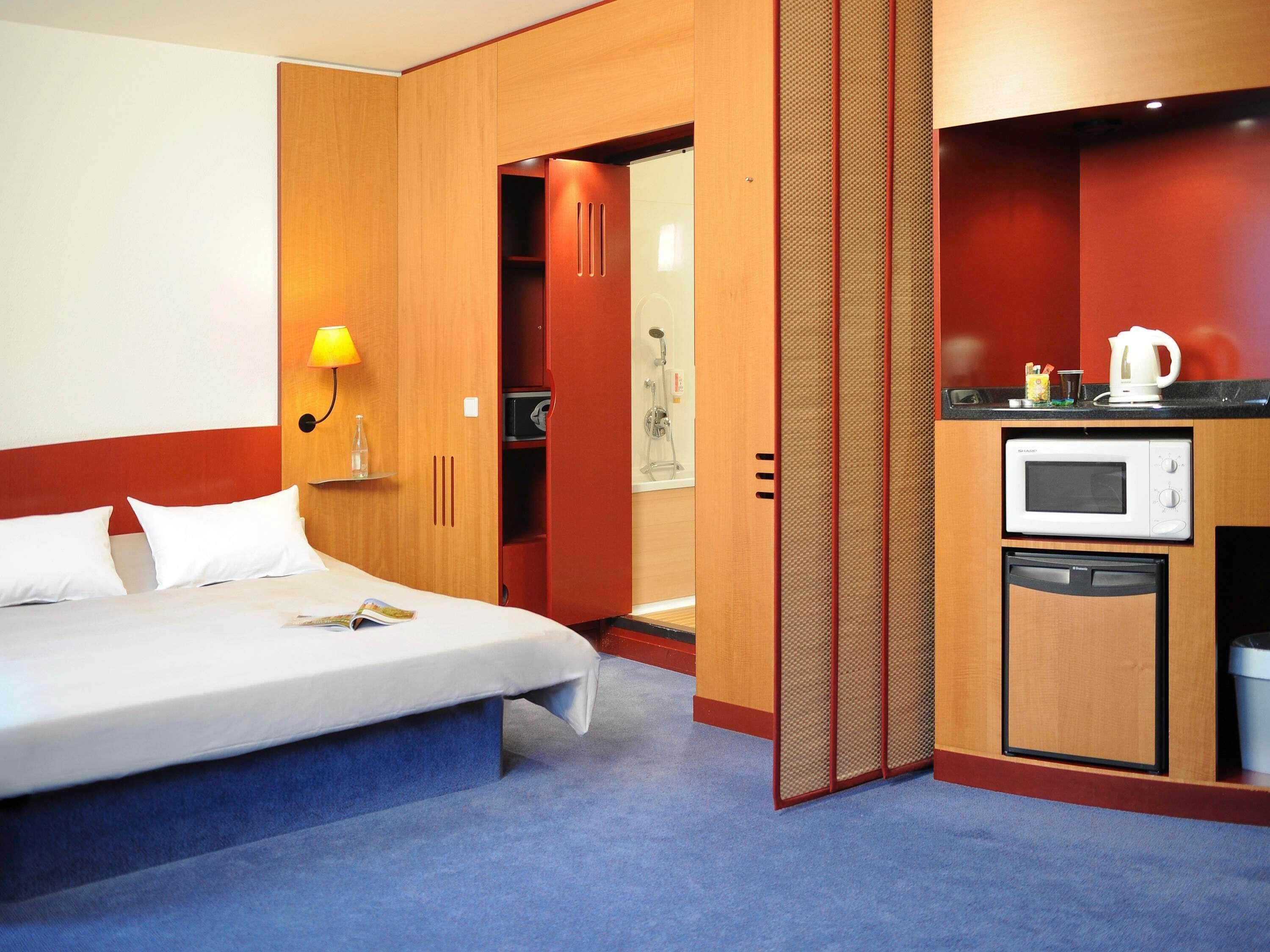 Ein Hotelzimmer mit Bett, einer Mikrowelle, einem kleinen Waschbecken und einer Duschkabine.