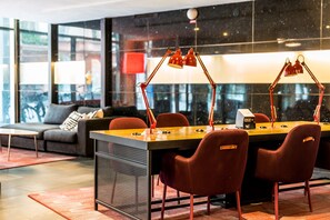 A modern meeting room with a wooden table, red chairs, and two red desk lamps. - Scandic St Jörgen (Malmö)