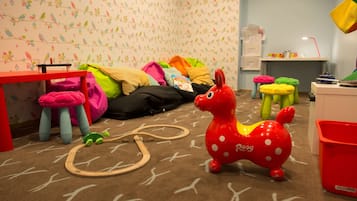 Children can play and explore in this vibrant playroom with a toy horse, train track, and colorful furniture.