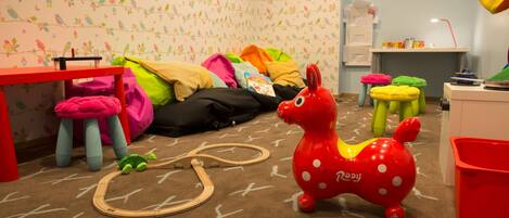 A child's playroom with a toy horse, colorful stools, and a play mat.