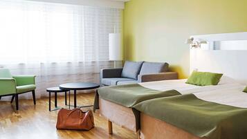 Una habitación de hotel con una cama, un sofá, una silla, una mesita y una lámpara.