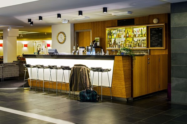 Eine Bar mit Theke, Hockstühlen, einer Uhr und einer Speisekarte.