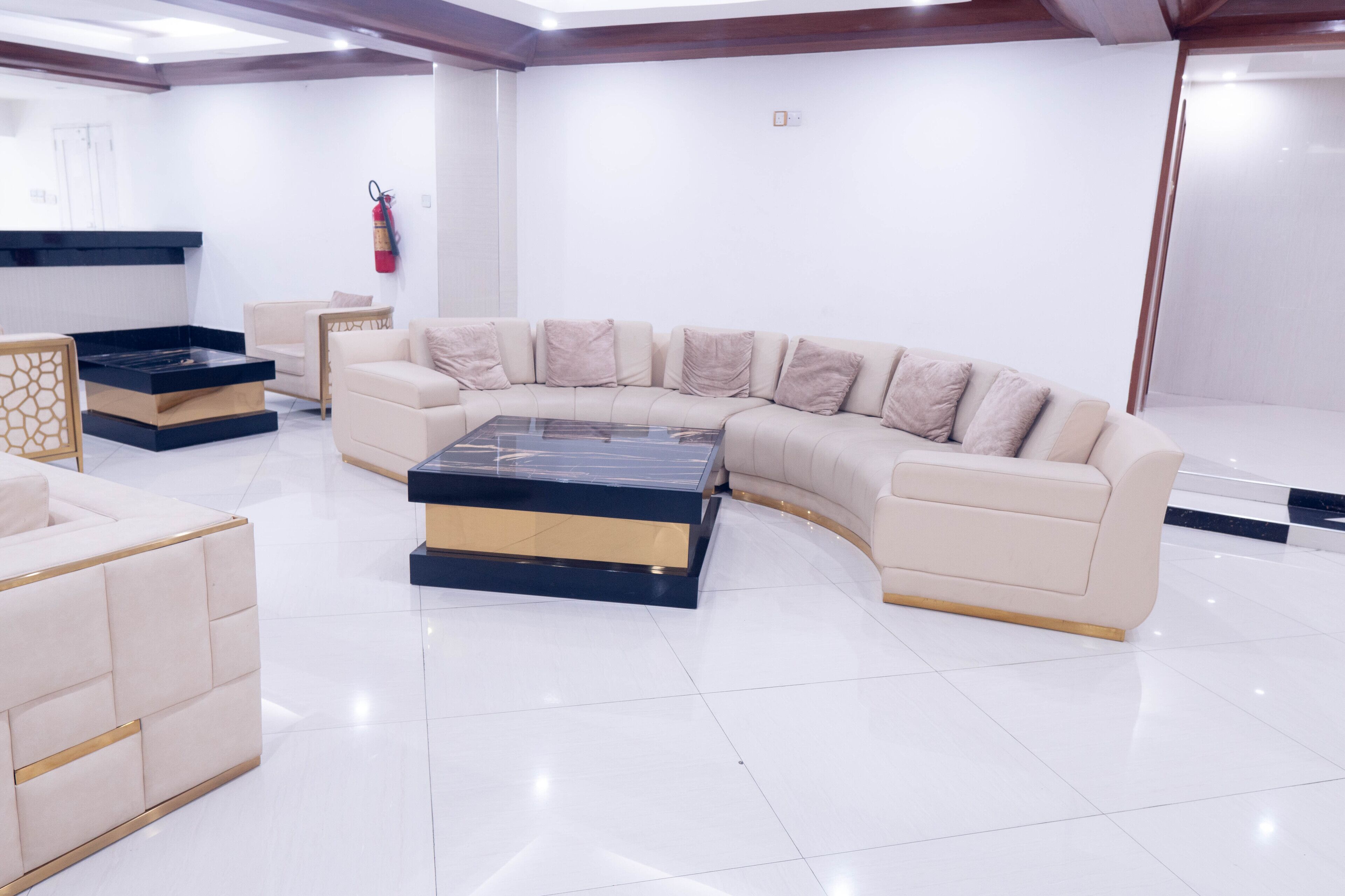 A modern living room with a curved sofa, a glass coffee table, and a fireplace.