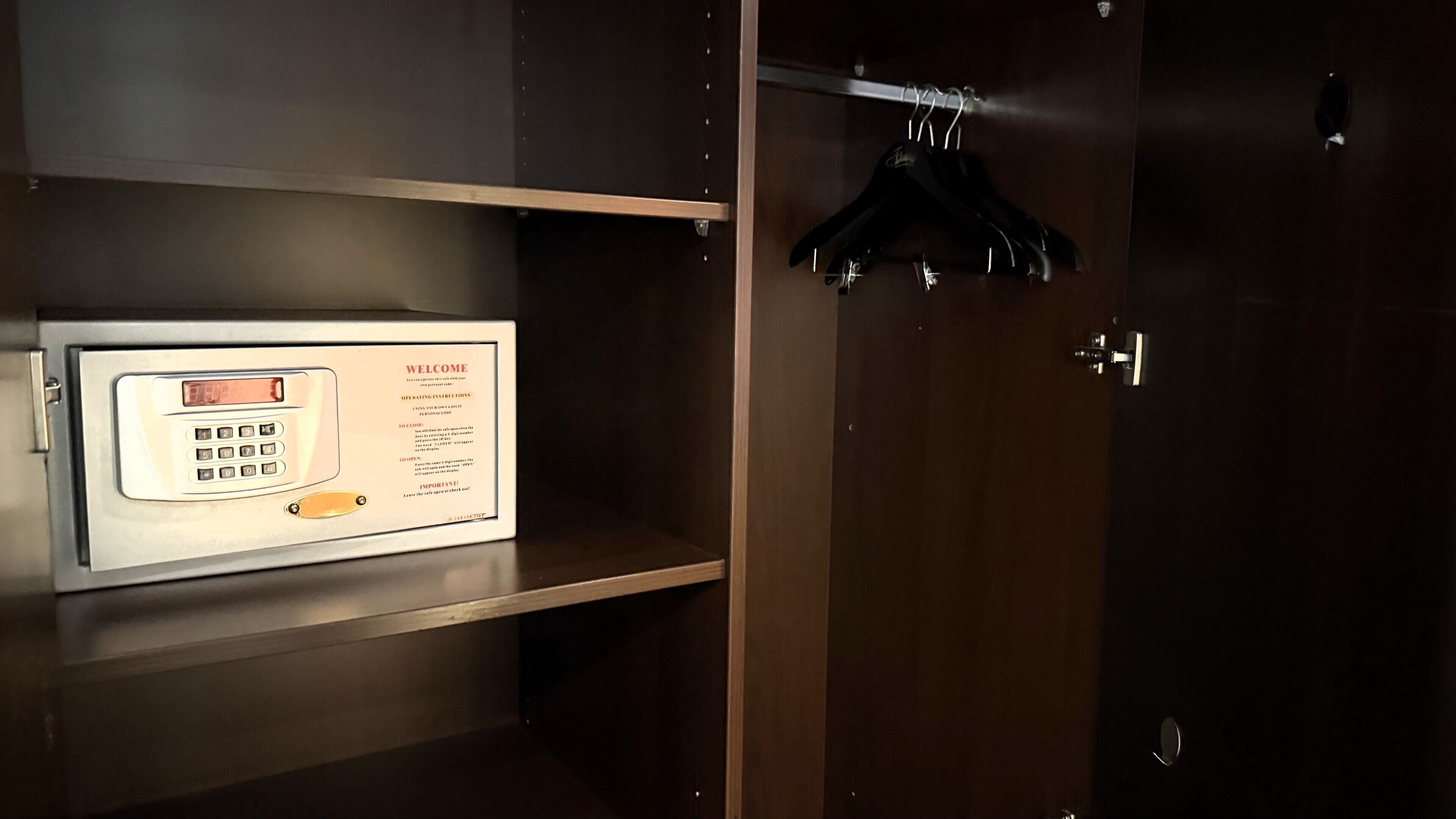 Una habitación con una caja fuerte digital, una puerta de madera y un perchero con ganchos.
