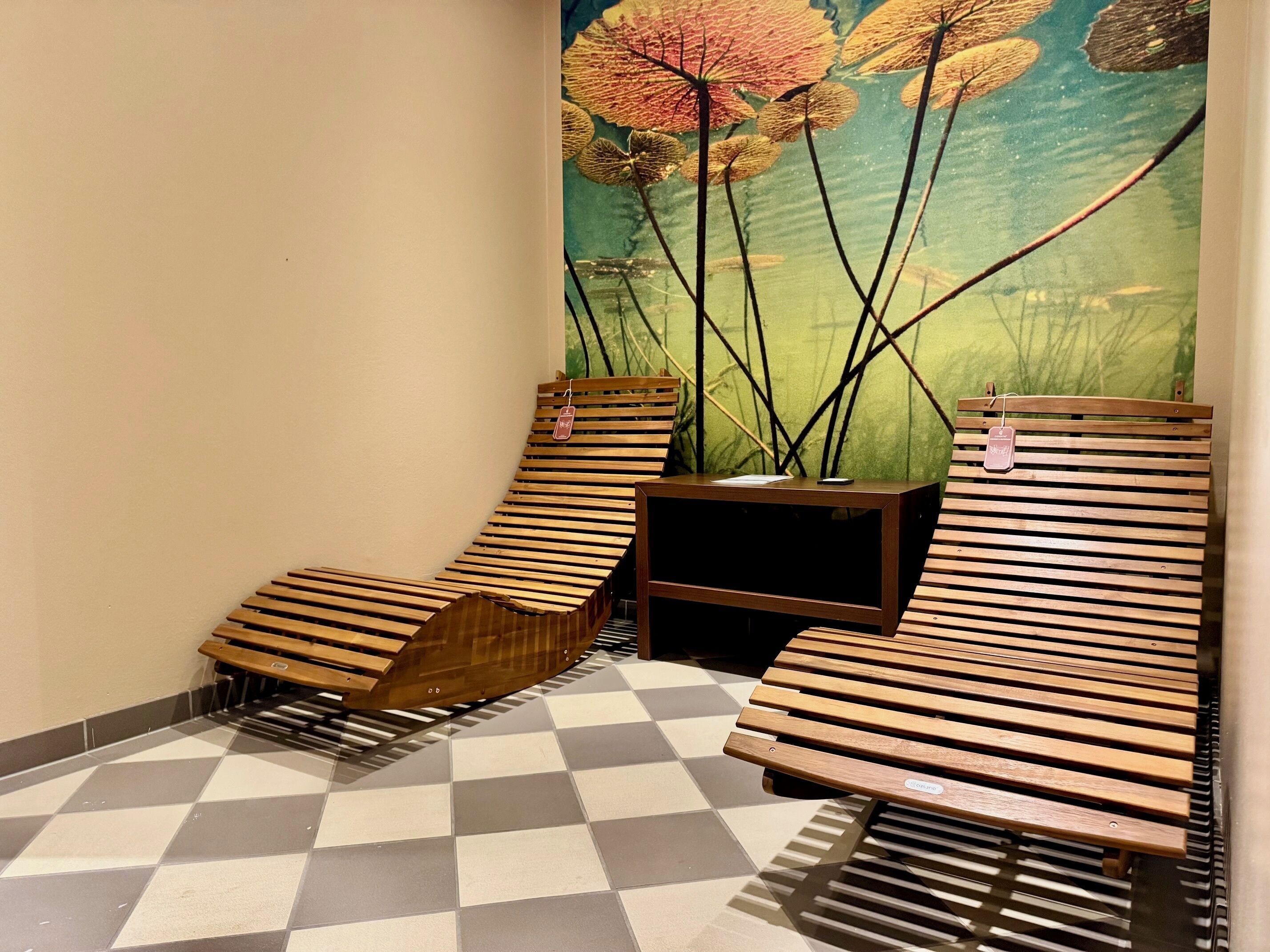 Una habitación con dos sillones de madera, una mesita y suelo a cuadros.