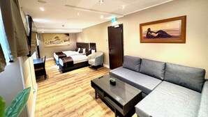 A modern hotel room with a bed, a sofa, a coffee table, and a painting on the wall. - Hotel Lumière an der Messe by ANS (Frankfurt)