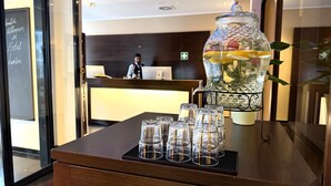 A reception desk with a glass fruit pitcher and several glasses on a tray. - Hotel Lumière an der Messe by ANS (Frankfurt)