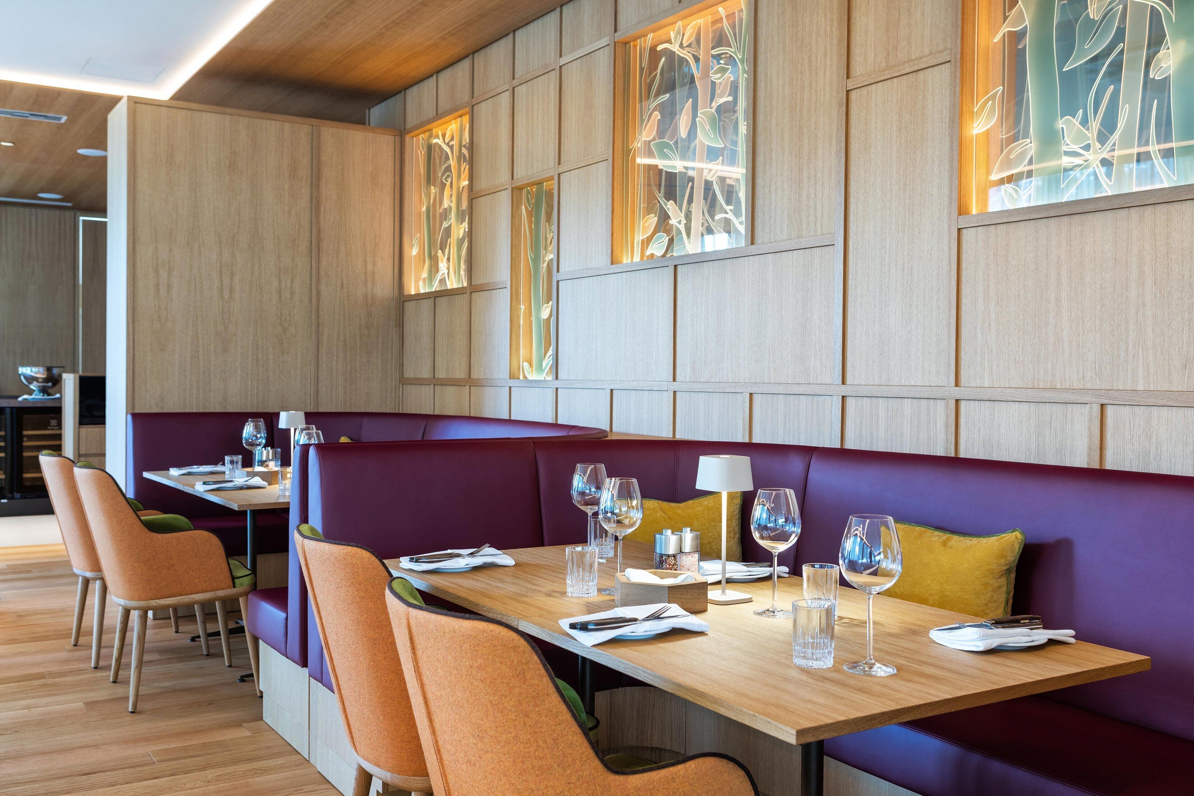 A restaurant with wooden panel walls, purple booths, and orange chairs.