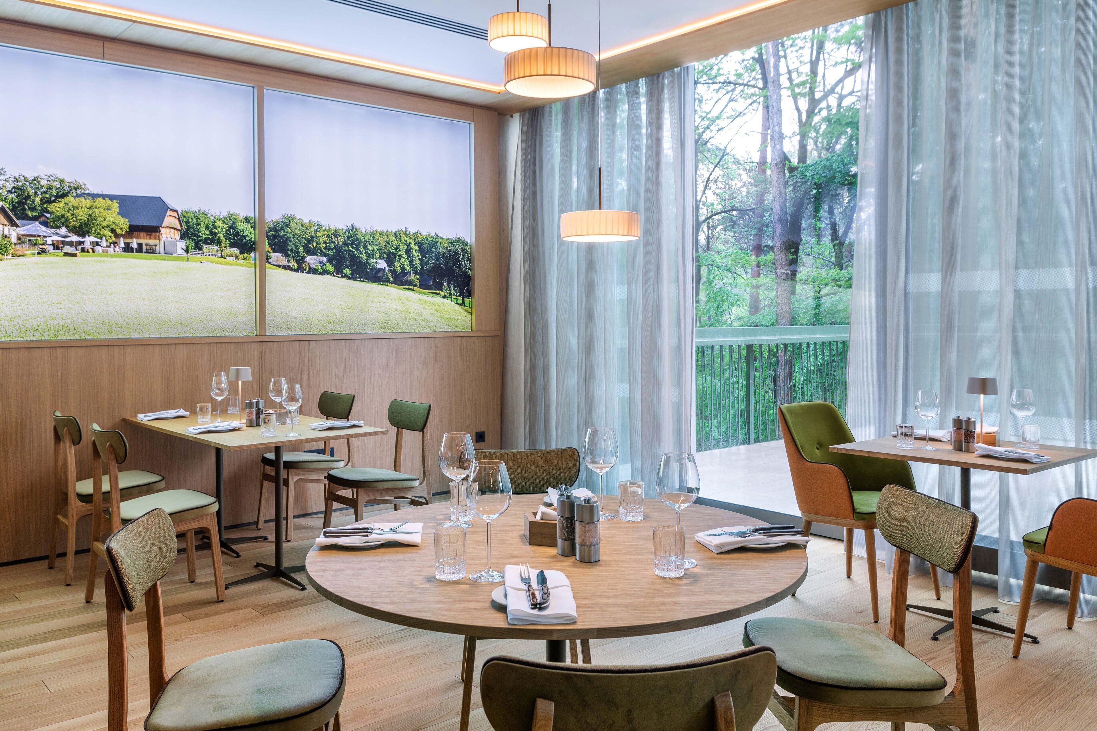 A dining area with round tables, chairs, and wine glasses.