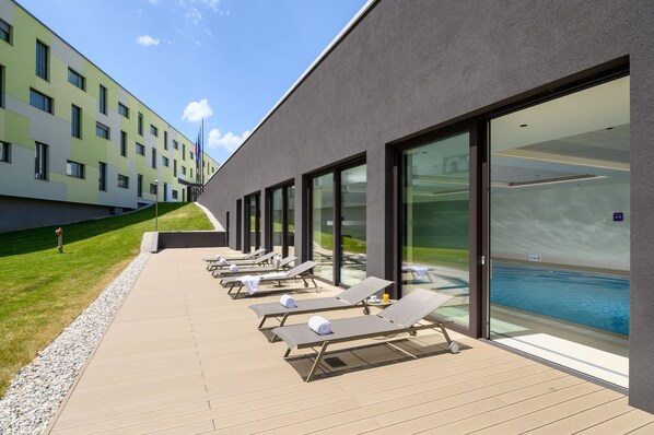 Un hotel moderno con zona de piscina que cuenta con tumbonas y una vista despejada de la piscina.