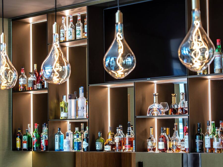 A bar area with multiple shelves of liquor bottles and hanging light fixtures.