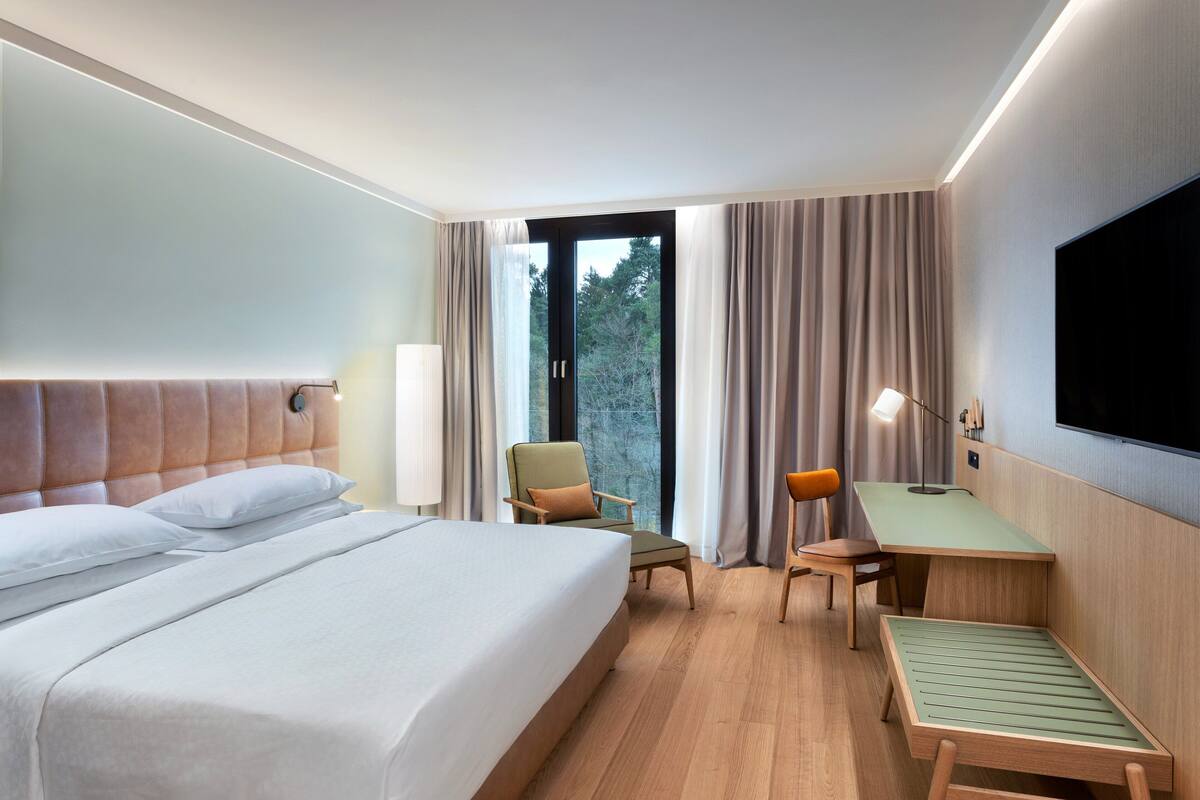 Ein Hotelzimmer mit Bett, Schreibtisch, Stuhl und Fernseher.
