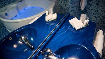 A bathroom with a blue marble sink, a white bathtub, and toiletries on the counter.
