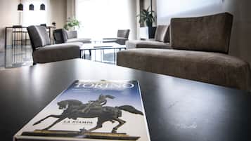 A book titled "Torino" on a table in a modern hotel lobby with seating and a plant.