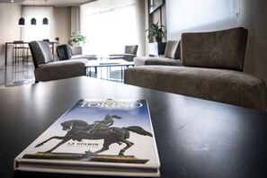 A book titled "Torino" on a table in a modern hotel lobby with seating and a plant. - Blu Hotel, Sure Hotel Collection by Best Western (Collegno)