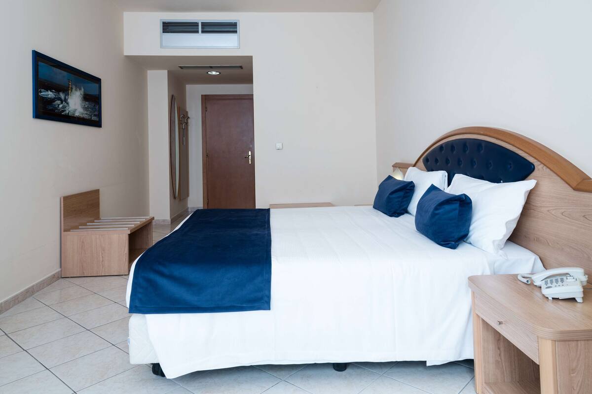 A hotel room with a bed, bedside table, and a phone.