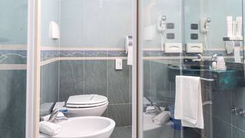 Un baño moderno con cabina de ducha de vidrio, inodoro blanco, lavamanos grande y tocador con superficie de vidrio.