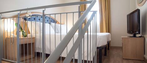 A hotel room with a bed, a bedside table with a lamp, a TV, and a wooden cabinet.