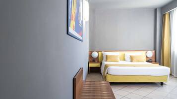 Una habitación de hotel con una cama, mesitas de noche, un banco y una obra de arte en la pared.
