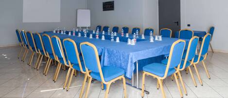 Une salle de conférence avec une longue table, des chaises bleues et un tableau blanc.