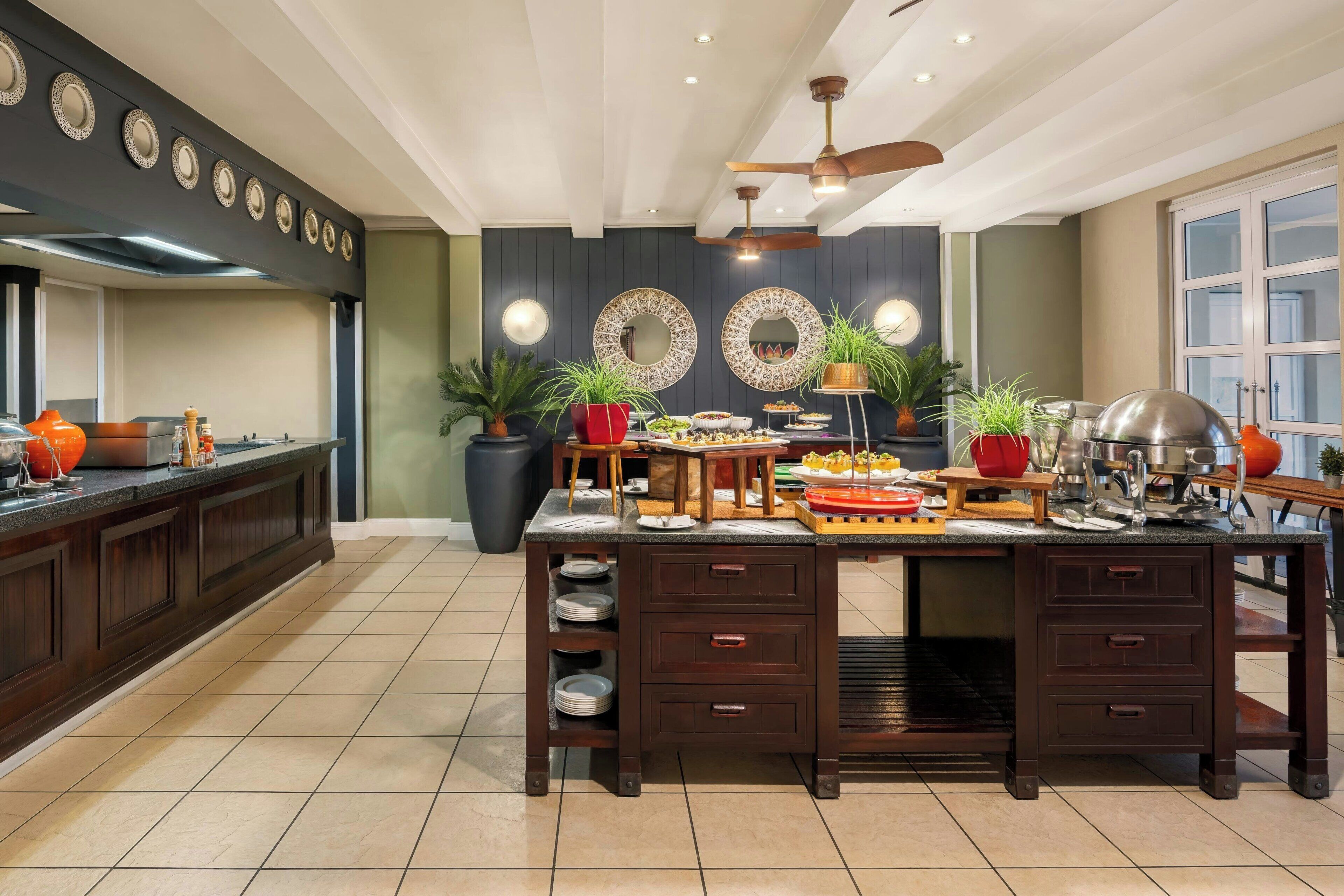 A kitchen with a central island, dark cabinetry, and decorative wall mirrors.