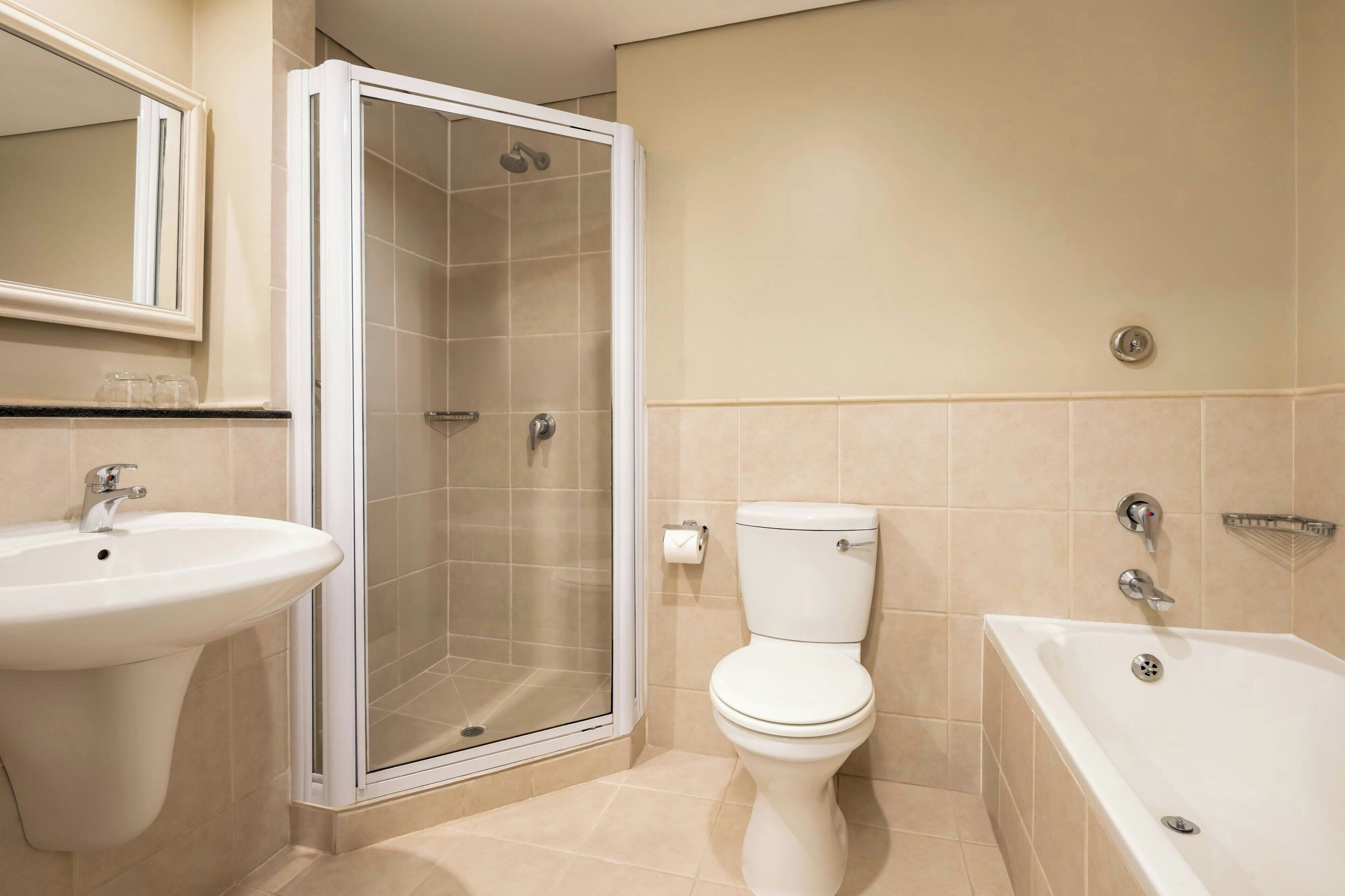 Et badeværelse med bruser, toilet, håndvask og badekar.