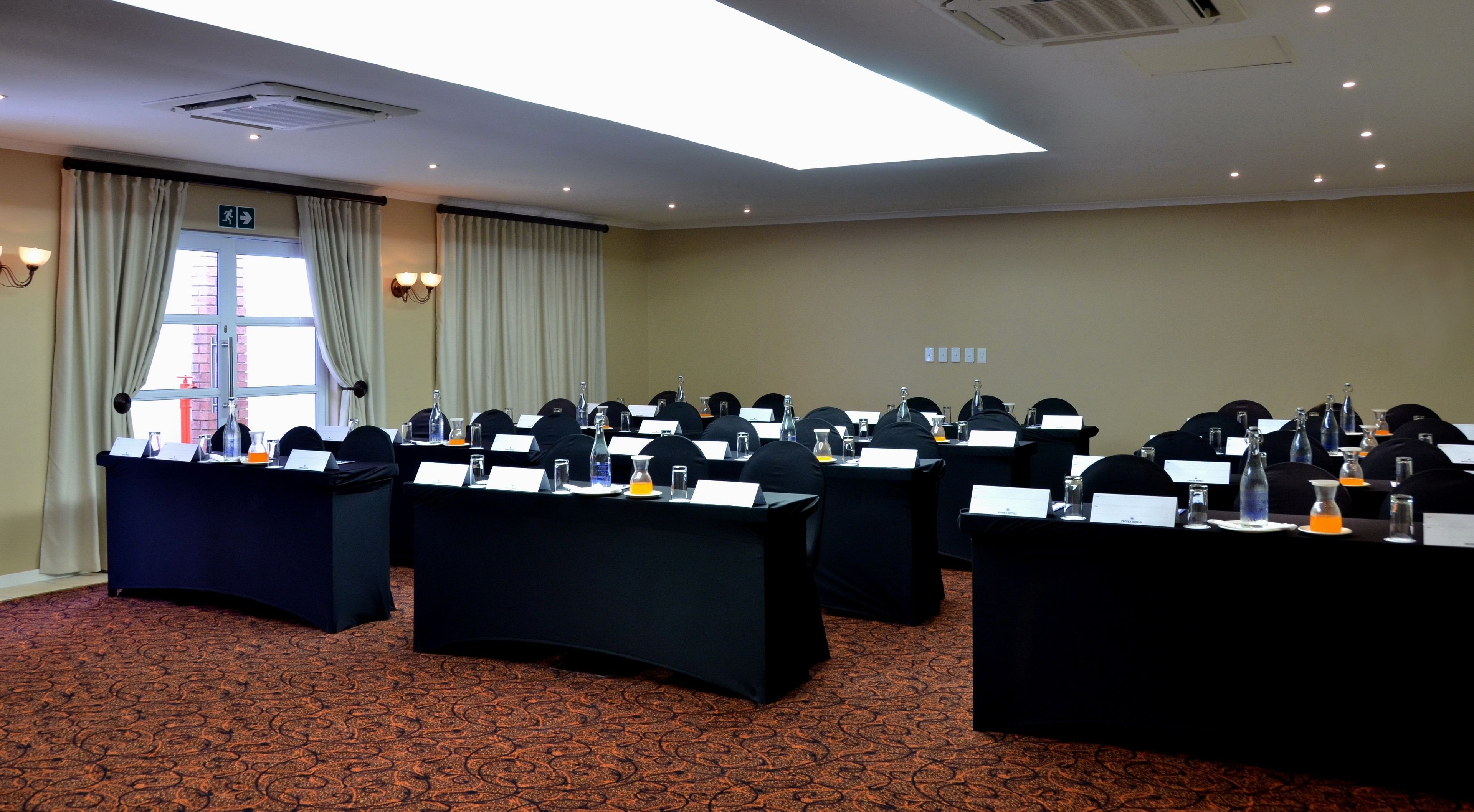 Una sala de conferències amb taules, cadires, matisos de noms i ampolles d'aigua.