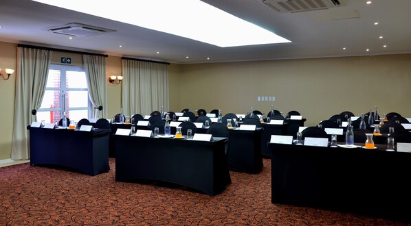 Un salón de conferencias con mesas, sillas, tarjetas de identificación y botellas de agua.