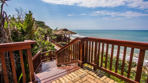 A wooden staircase leading to a beach area with a wooden gazebo. - Imvubu Lodge (Richards Bay)