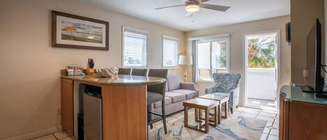 A modern kitchen with a built-in refrigerator, a dining area with a sofa and chairs, and a ceiling fan.