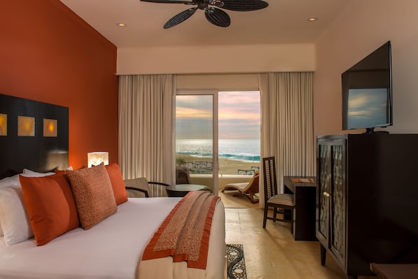 Habitación de hotel con cama, escritorio, televisión y vista a la playa.