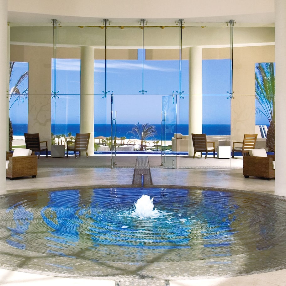 A spacious lobby with a central water feature, large windows offering ocean views, and seating areas.