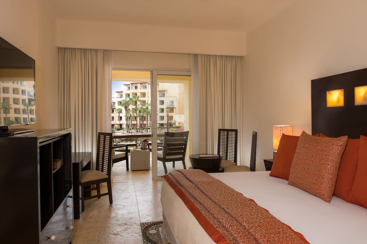 Une chambre d’hôtel avec un lit, un bureau, une chaise et une vue sur le balcon extérieur.