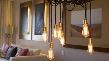 A living room with a sofa, a chandelier with multiple light bulbs, and artwork on the wall.