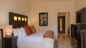 A hotel room with a bed, a TV, a painting, and a lamp.