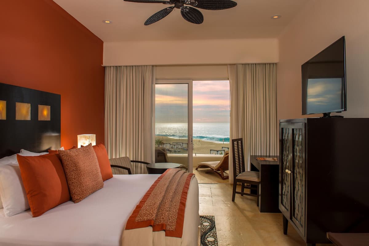Habitación de hotel con cama, televisión, escritorio y vistas a la playa.