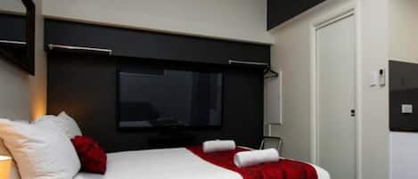 Et moderne hotelværelse med seng, natbord, spejl og garderobeskab.