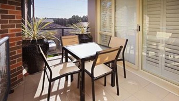 A balcony with a table and chairs, potted plants, and a sliding glass door. - Jesmond Executive Villas (Jesmond)