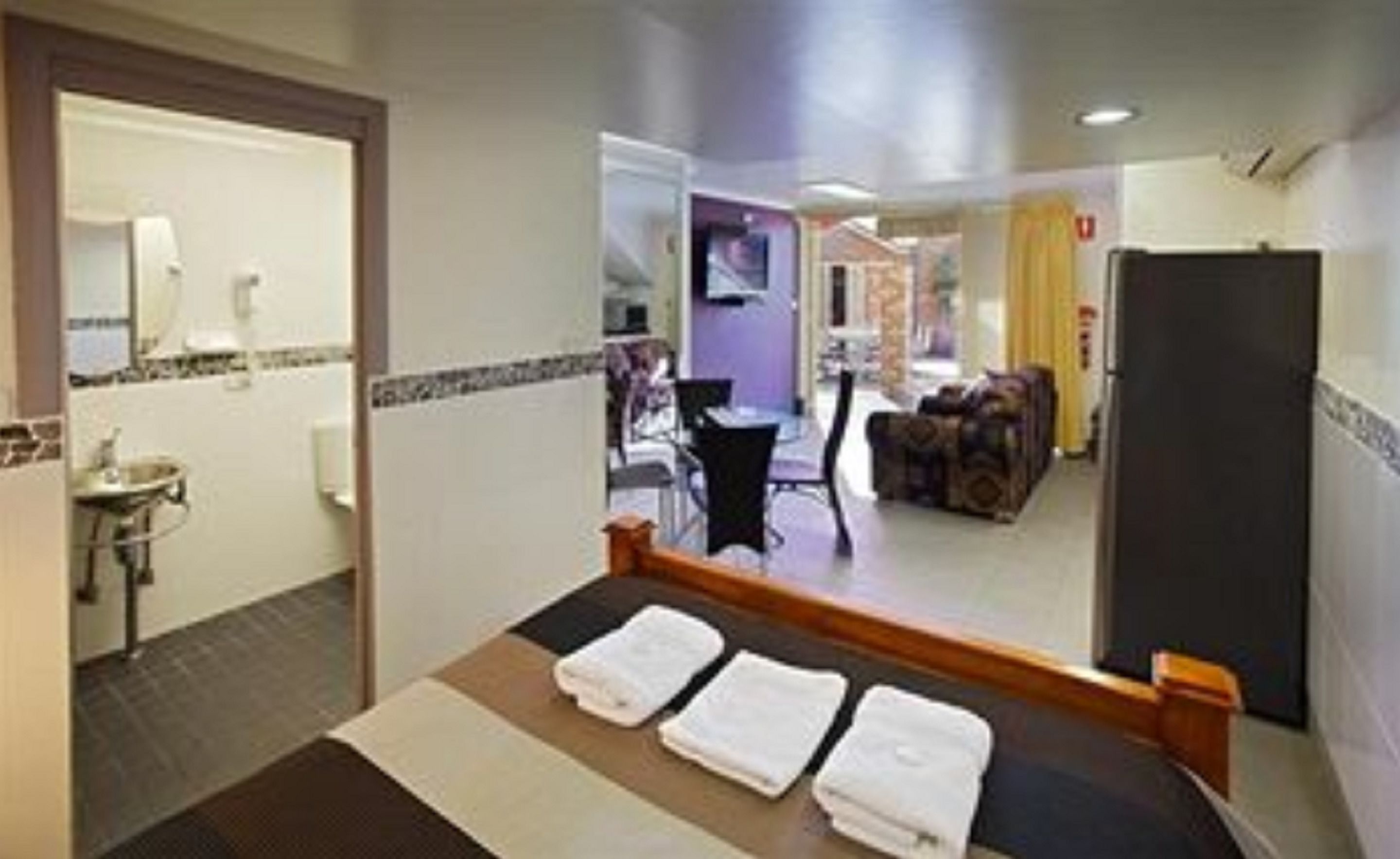 Une chambre d’hôtel avec un lit, un lavabo, un miroir et une vue sur le couloir.