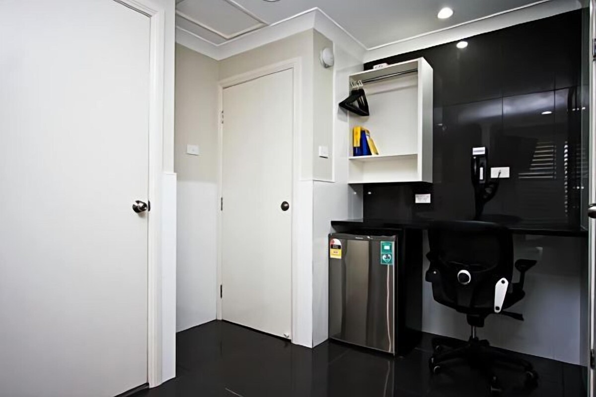 A modern office space with a white door, a compact refrigerator, and a black office chair.