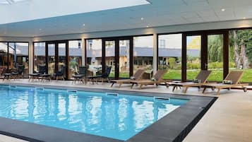 Een binnenzwembad, ligstoelen bij het zwembad