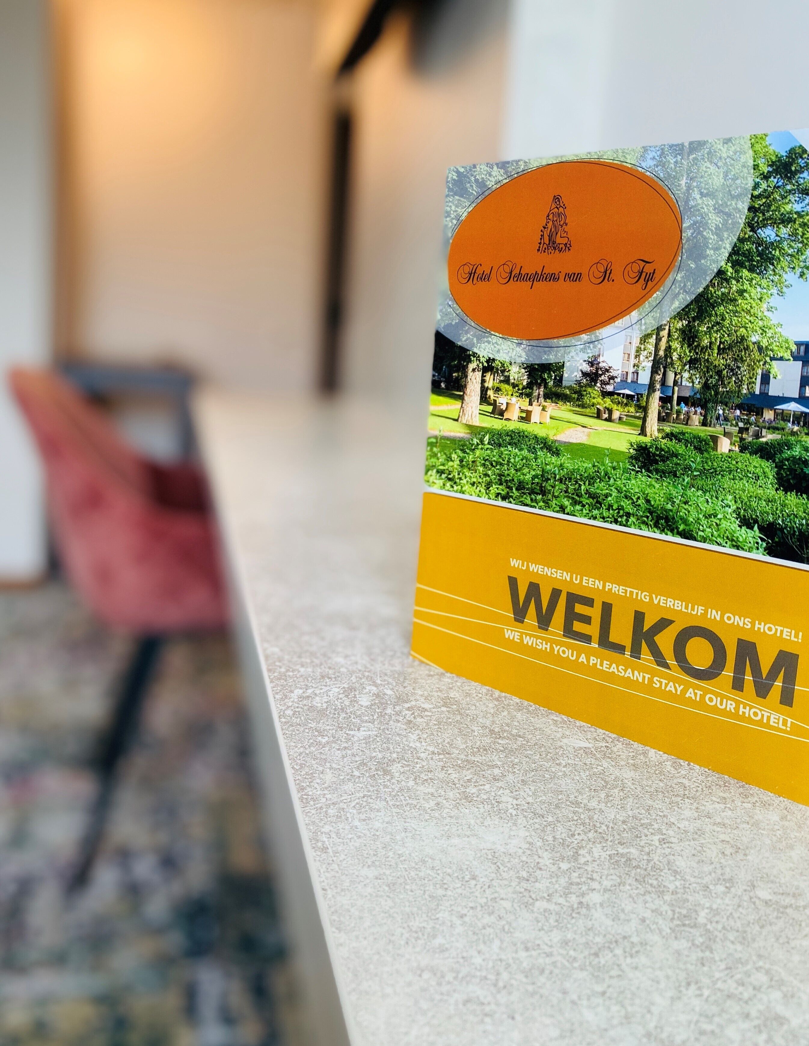 A reception desk with a welcome sign featuring a garden view and a sign reading "Adel Schaapkens van St. Pieter".