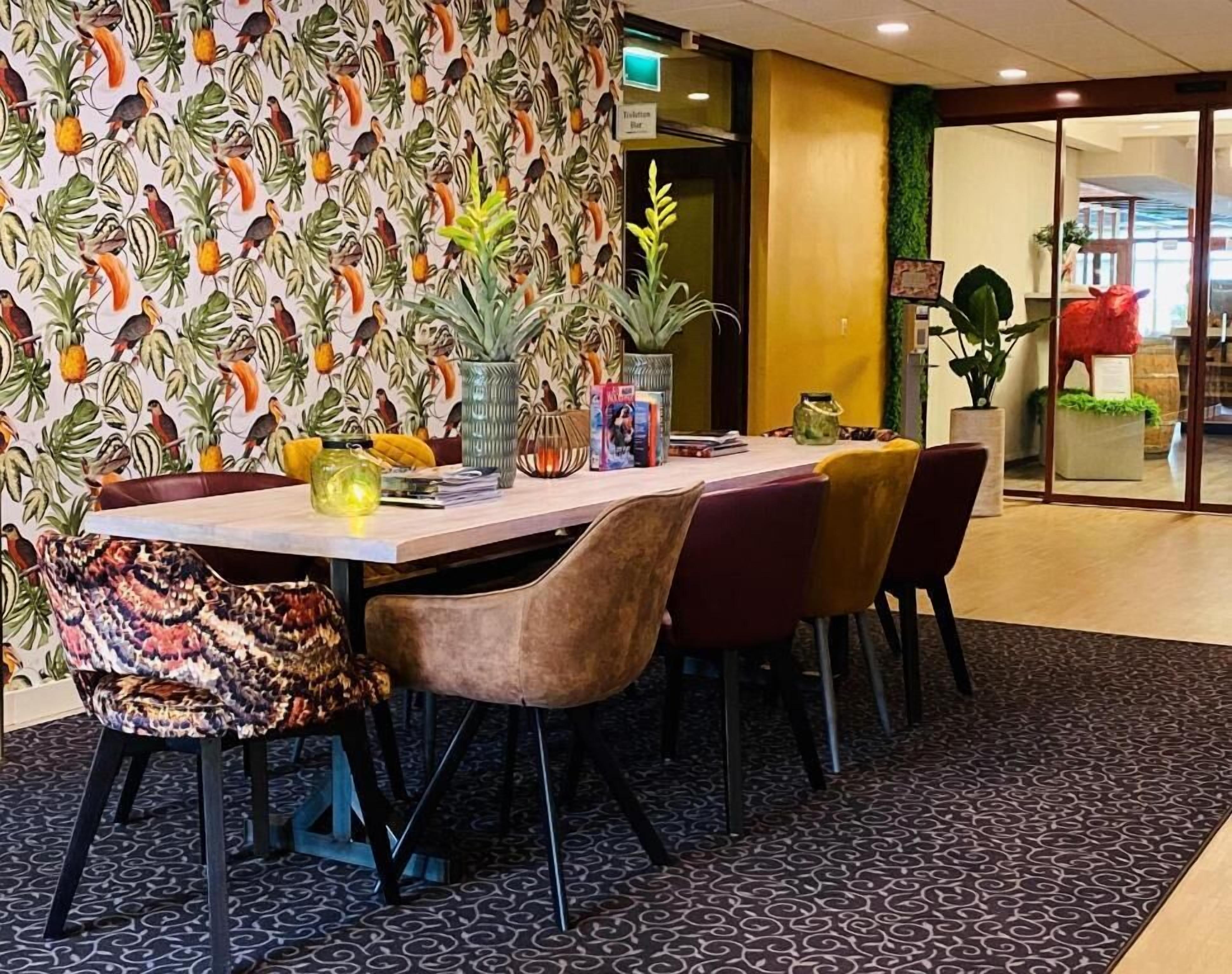 Un coin repas avec un papier peint à motifs, une table avec des chaises et un sol recouvert d’une moquette.