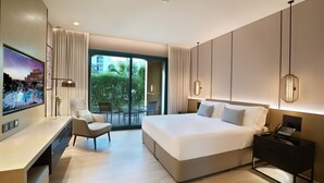 A modern hotel room with a large bed, a desk, a chair, and a TV displaying a cityscape. - Al Ain Rotana (Al Ain)