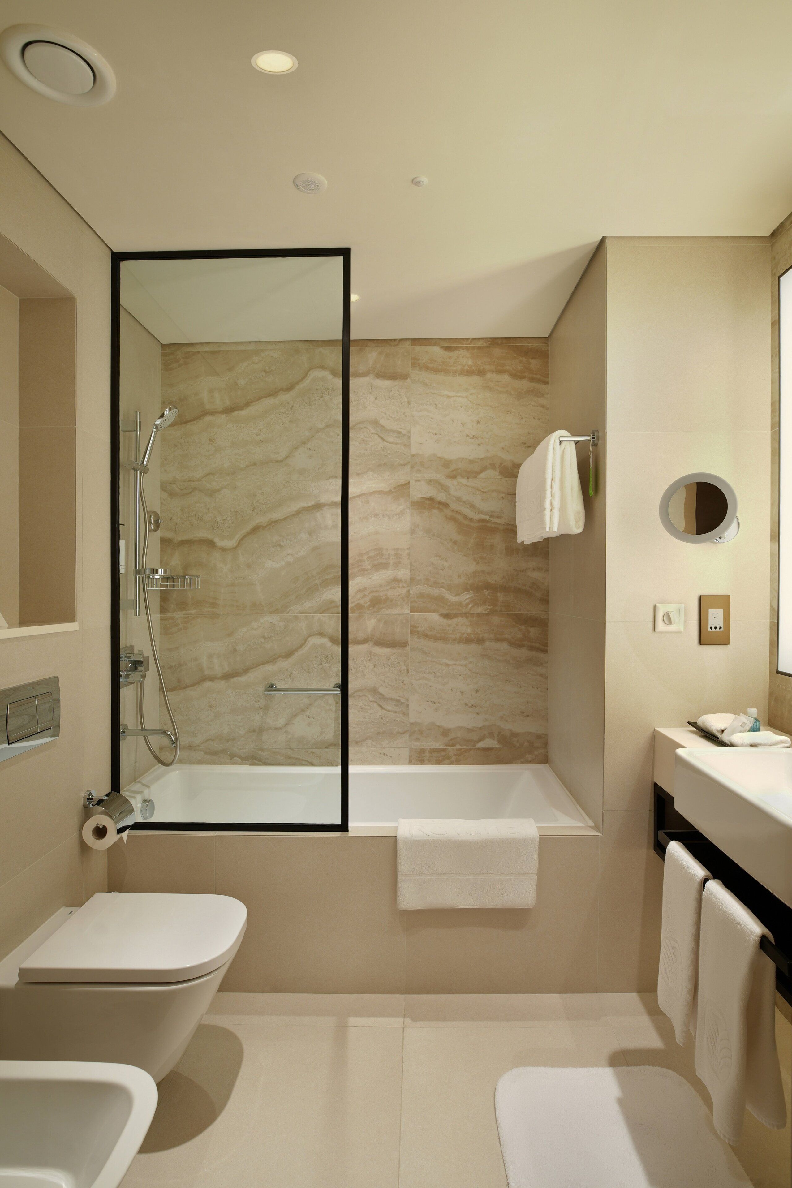 Un baño moderno con ducha de vidrio, bañera, inodoro y tocador con espejo.