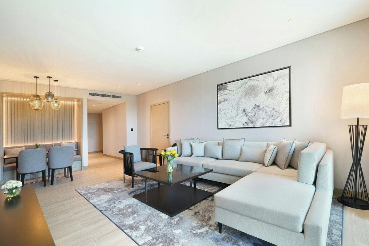 A modern living room with a sofa, coffee table, and dining area.