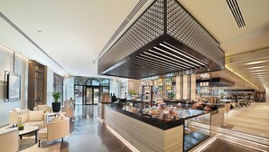 A modern hotel lobby with a central counter, seating area, and a decorative ceiling. - Al Ain Rotana (Al Ain)