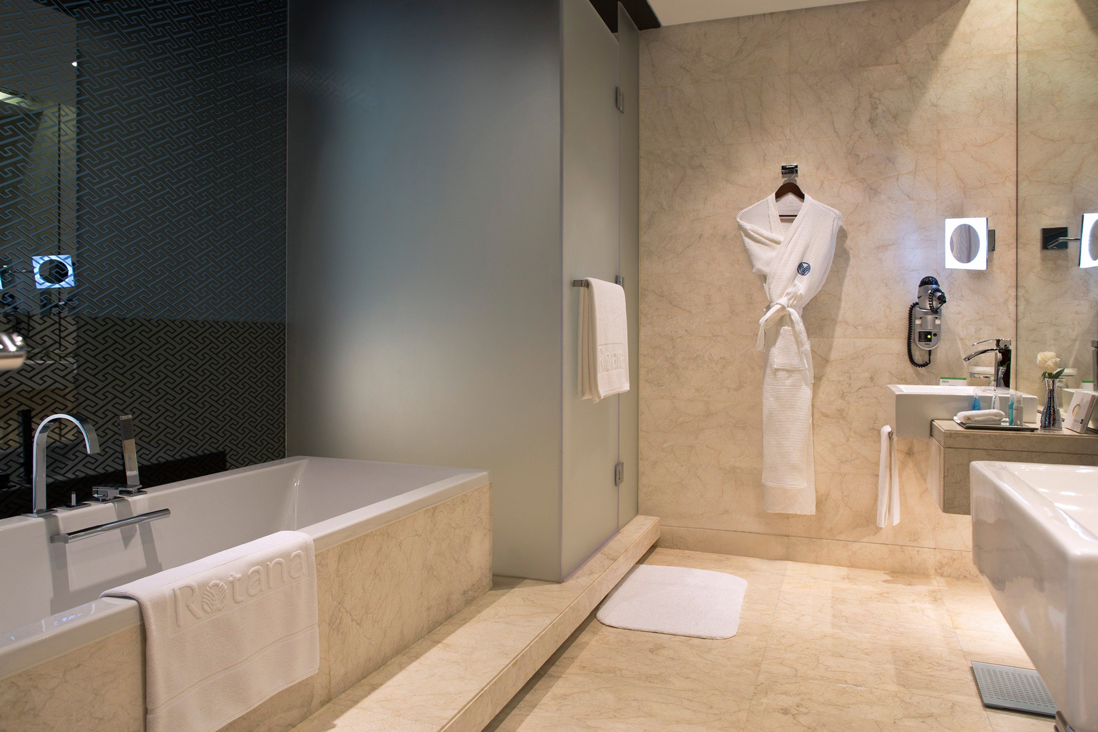 A modern bathroom with a bathtub, a sink, and a mirror.