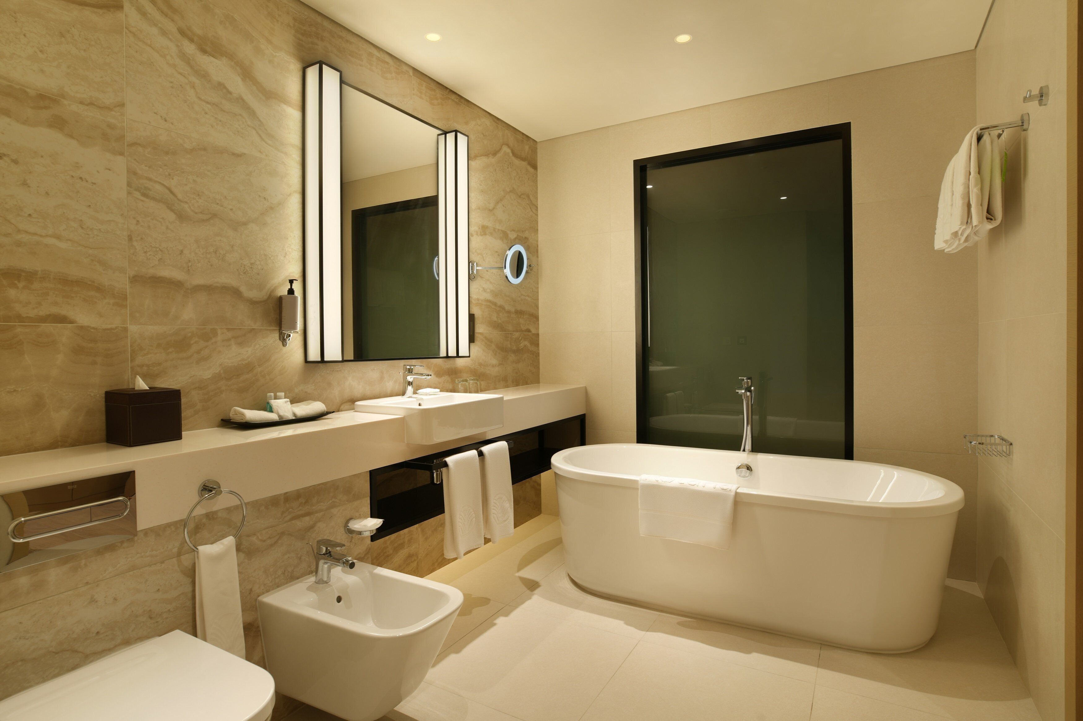 Un baño moderno con una bañera independiente, un lavabo, un bidé y un espejo grande.